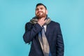 Young adult man with beard wearing official style suit, being wrapped in scarf, touching his neck Royalty Free Stock Photo