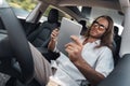 Young adult man with beverage sitting in car, using tablet computer Royalty Free Stock Photo