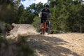 Young adult man bicycles along a dirt path in a lush green forest