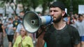 Angry protester with bullhorn walks and talks. Shouting with megaphone activist