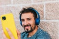 Young adult man dressed in sportswear using his yellow smartphone to take a selfie photo while listening to music with his Royalty Free Stock Photo