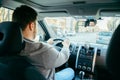 Young adult man driving car by city streets using phone as navigation Royalty Free Stock Photo