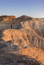 Young adult man flying drone in semi-desert area with erosional figures and cliff