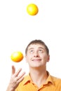 Young adult man juggle with oranges