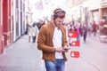 Young Adult Man Listening Music on Smartphone and Headphone on The Street at Summer Time