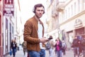 Young Adult Man Listening Music on Smartphone and Headphone on The Street at Summer Time