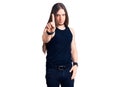 Young adult man with long hair wearing goth style with black clothes pointing with finger up and angry expression, showing no