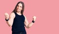 Young adult man with long hair wearing rocker style with black clothes and contact lenses screaming proud, celebrating victory and Royalty Free Stock Photo