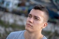 Young adult man sitting calmly and looking into the distance with a troubled look. Close headshot