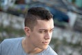 Young adult man sitting calmly and looking into the distance with a troubled look. Close headshot