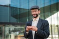 Young adult man using a cellphone app at workplace. Bearded cool guy having fun with a smartphone device. Caucasian Royalty Free Stock Photo