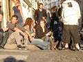 Young adult men and women sitting on street corner as sun sets Royalty Free Stock Photo