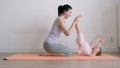 Young adult mom teaching her little baby to practise yoga at home Royalty Free Stock Photo