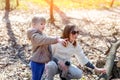 Young adult mother and little daughter walking together in forest or park on bright sunny day. Cute blond baby girl pointing with Royalty Free Stock Photo