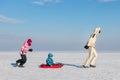 Young adult mother wear warm jacket enjoy have fun sledging two cute little sibling kids boy girl at frozen white snow Royalty Free Stock Photo