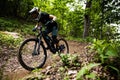Young adult mountain biker wearing a protective helmet rides through a scenic wooded landscape