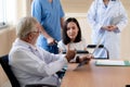 Patient in wheelchair discuss her health with doctor in sterile room.