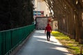 Young adult in a red hoodie seen from behind walking alone on the pavement during the corona virus outbreak. Moody environment ,