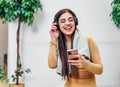 Young adult smiling cheerful girl woman listening to music from smartphone wearing wireless headset headphones and dancing while Royalty Free Stock Photo