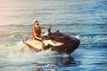 Young adult sporty caucasian woman riding jet ski in ocean blue water at warm evening sunset. Beach extreme sport activities and Royalty Free Stock Photo