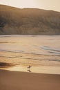 Young adult standing on a sandy beach in front of an awe-inspiring sunset