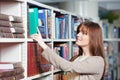 Young adult student selecting book in library