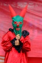 a person with a horned mask and costume holding an umbrella