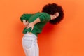 Young adult woman with Afro hairstyle wearing green casual style sweater suffering from lower back pain, pinched nerve or kidney Royalty Free Stock Photo