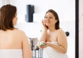 Young adult woman apply facial cream look in mirror Royalty Free Stock Photo