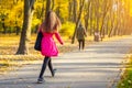 Young adult woman in bright casual coat walking along beautiful golden colored autumn park alley. Happy attractive sporty girl in Royalty Free Stock Photo