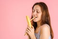 A young adult woman cleans the banana peel with her teeth, covering her eyes with pleasure. The concept of female erotic fantasies