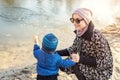 Young adult woman with cute toddler boy having funfeeding birds near lake or pond at city park on bright atumn day Royalty Free Stock Photo