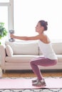 Young adult woman doing fitness exercises with gray dumbbells at her home in living room Royalty Free Stock Photo