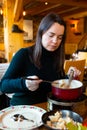 Young adult woman eating fondue at restaurant Royalty Free Stock Photo