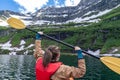 Young adult woman kayaks on Cameron Lake in Waterton National Park, enjoying the glacier scenery