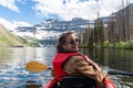 Young adult woman kayaks on Cameron Lake in Waterton National Park, enjoying the glacier scenery