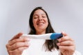 Young adult woman looking at pregnancy test with happy expression in her bedroom. latino woman with dark hair in her thirties Royalty Free Stock Photo