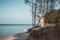 Young adult woman in pink hat sitting alone on the bluffs, looking of sea, freedom concept, peaceful atmosphere Royalty Free Stock Photo