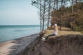 Young adult woman in pink hat sitting alone on the bluffs, looking of sea, freedom concept, peaceful atmosphere Royalty Free Stock Photo