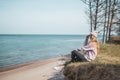 Young adult woman in pink hat sitting alone on the bluffs, looking of sea, freedom concept, peaceful atmosphere Royalty Free Stock Photo