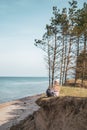 Young adult woman in pink hat sitting alone on the bluffs, looking of sea, freedom concept, peaceful atmosphere Royalty Free Stock Photo