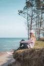 Young adult woman in pink hat sitting alone on the bluffs, looking of sea, freedom concept, peaceful atmosphere Royalty Free Stock Photo