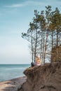 Young adult woman in pink hat sitting alone on the bluffs, looking of sea, freedom concept, peaceful atmosphere Royalty Free Stock Photo