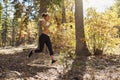 Young adult woman running in a forest jumps fallen branches