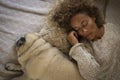 Young adult woman sleep at home in bed with her pug dog together on bed. Tired woman with dog lying on bed. Top view of tired