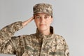 Young adult woman soldier saluting with hand near head, looking at camera with pleasant facial experession, wearing military Royalty Free Stock Photo