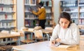 Young adult woman studying in public library Royalty Free Stock Photo