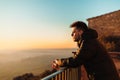 young adventurer resting on a railing on top of a hermitage, watching a beautiful cloudless sunset in the sky in Lleida Royalty Free Stock Photo