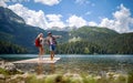 Young adventurous couple holding hands and excited on wooden jetty by lake. Pointing to distance. Love, adventure, hiking, nature Royalty Free Stock Photo