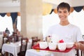Young affable waiter keeps tray at restauran